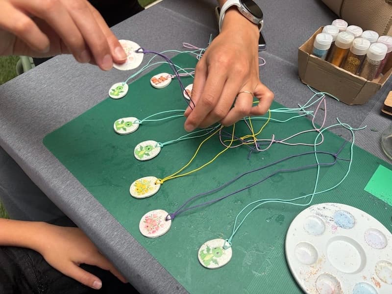Pendentifs en argile peints de fleurs et de dinosaures, enfilés sur des cordons colorés