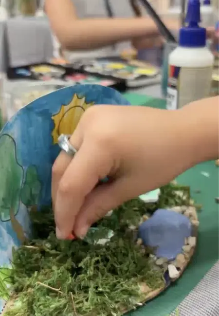 Main d'un enfant faisant une activité créative Montessori à Toulouse